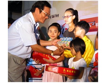 Le Thanh Dai (L), deputy editor-in-chief of SGGP Newspaper, presents moon cakes and other presents to children at the SOS Village in HCMC on September 9 (Photo: SGGP)